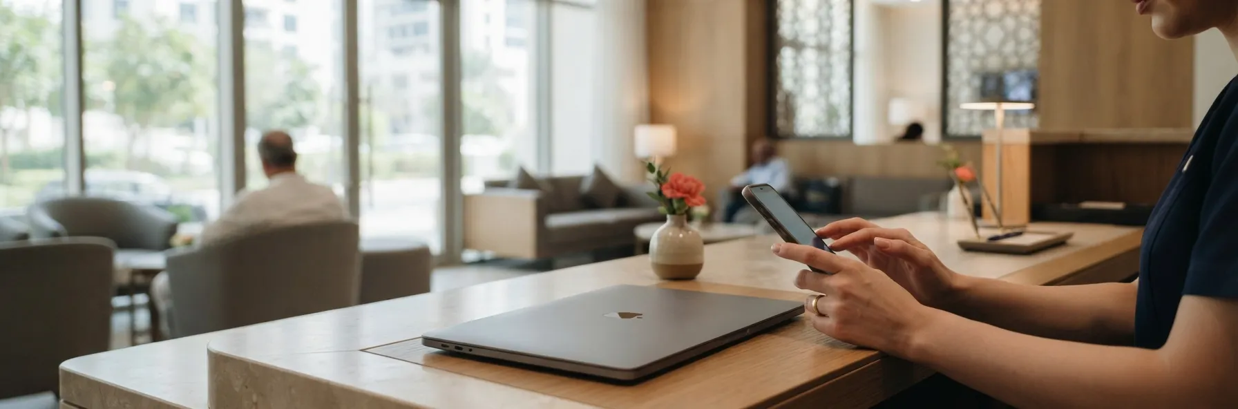Clinic staff member checking a WhatsApp enquiry on a phone at the front desk