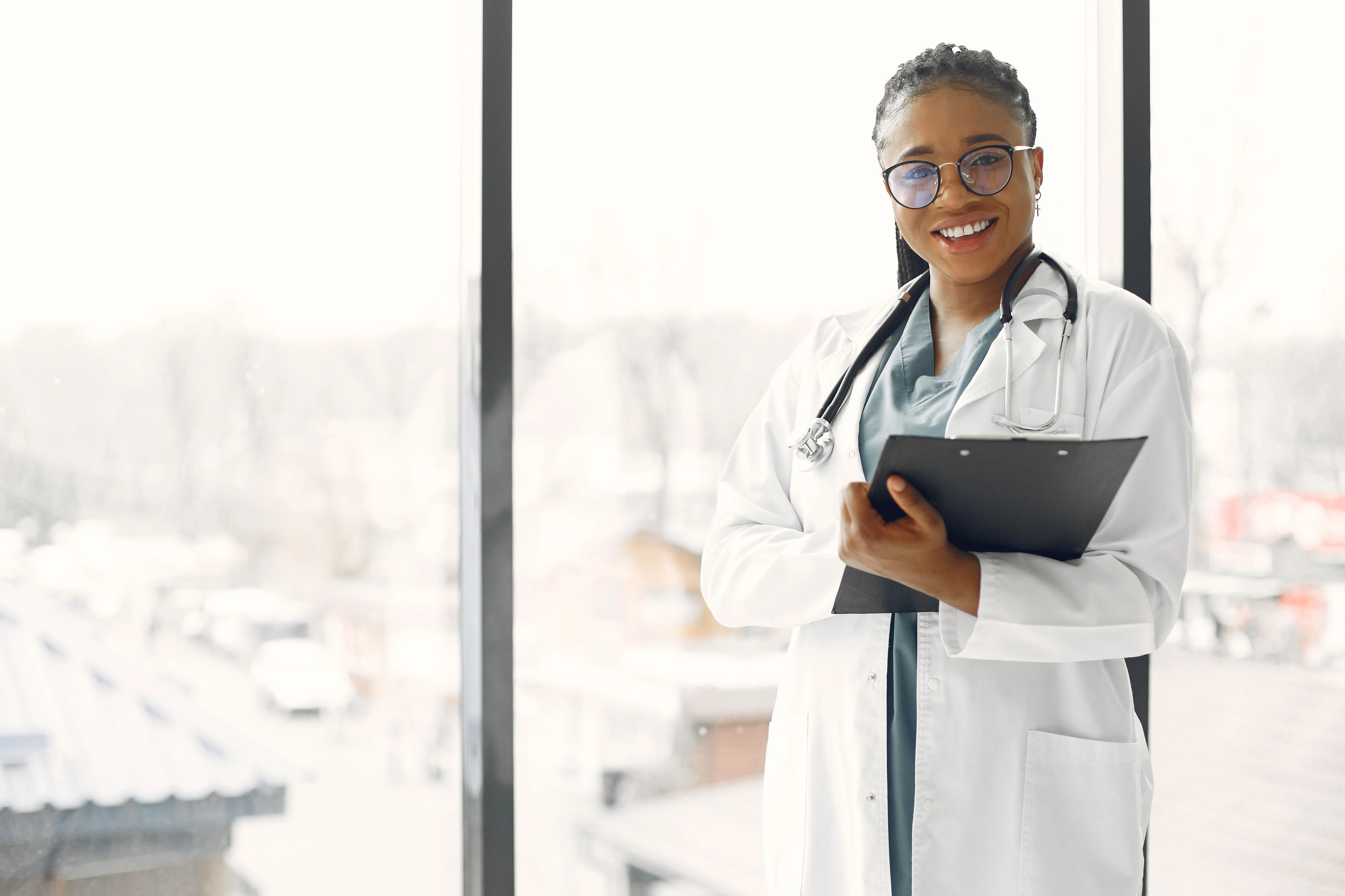 Smiling medical clinic doctor holding a clipboard in a bright consultation room
